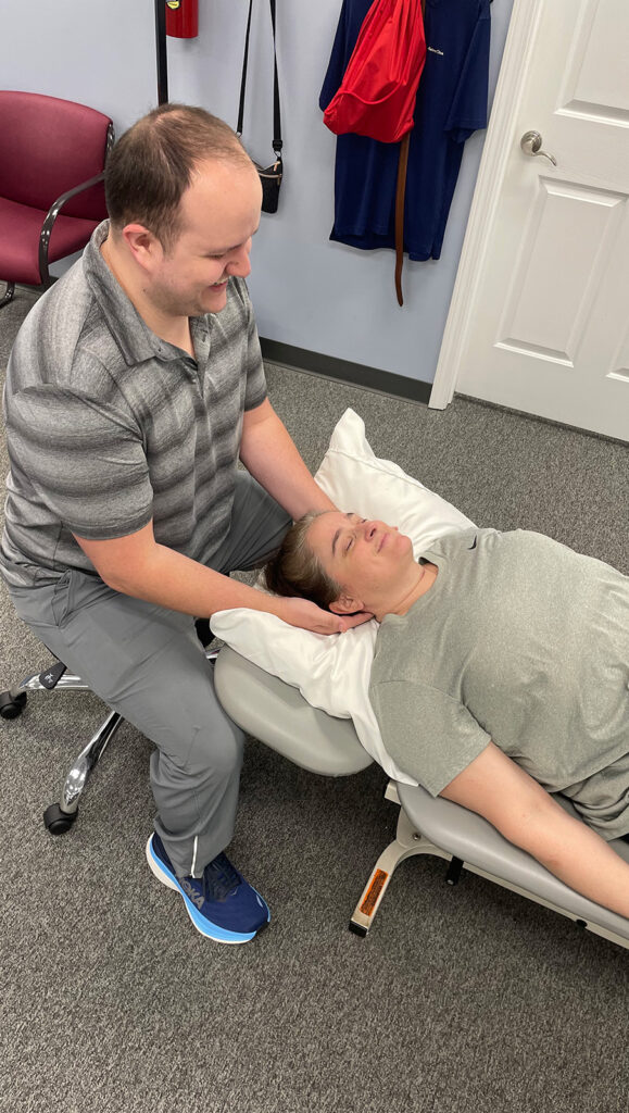 physical therapist at Taylor Rehab performing a neck physical therapy exercise for his patient